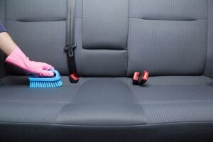 Cleaning a car's textile seats with professionally brush